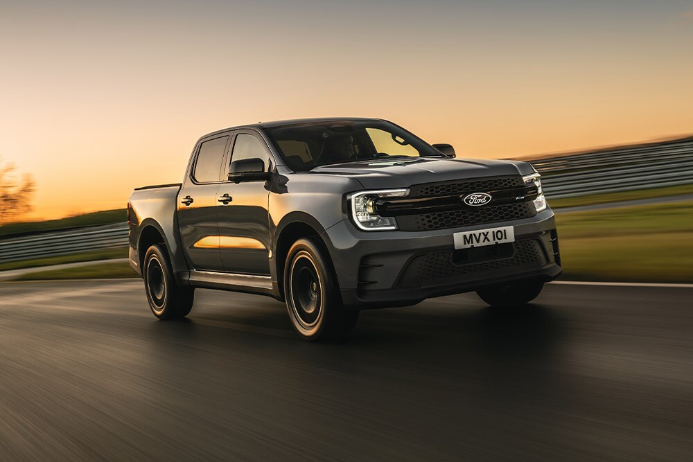 Ein dunkelgrauer Ford Ranger Platinum fährt bei Sonnenuntergang auf einer Strecke.