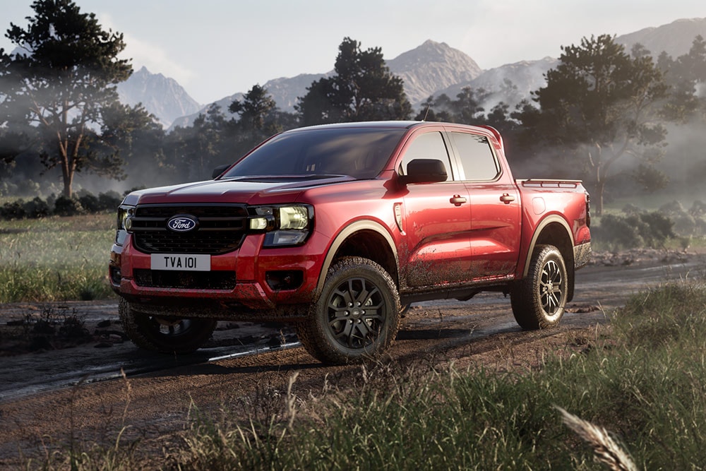 Ein roter Ford Ranger Raptor fährt auf einer unbefestigten Strasse durch eine malerische Landschaft.