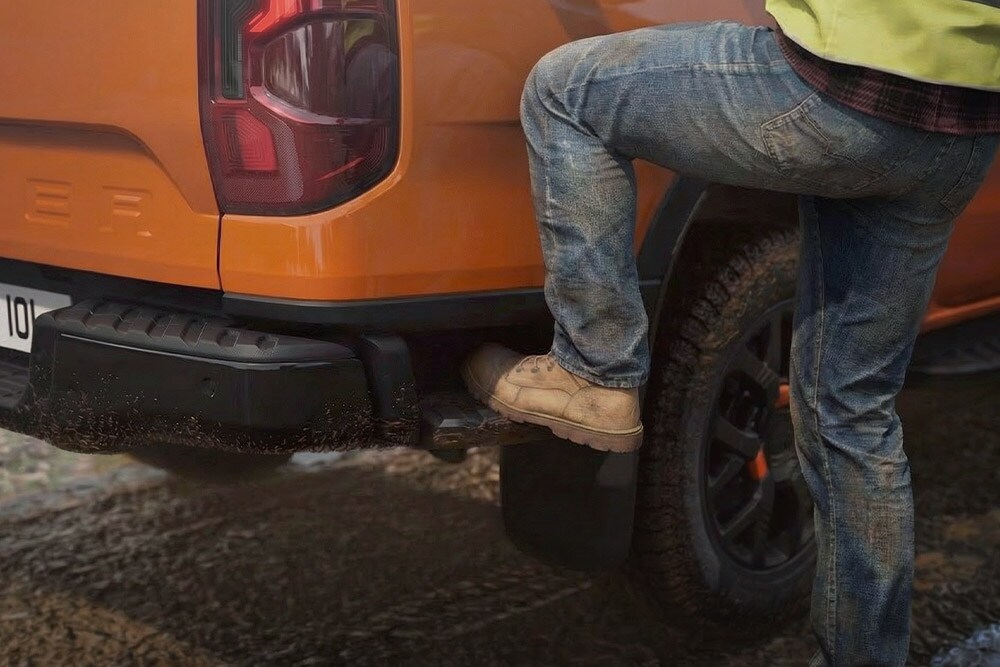 Ein Arbeiter steigt auf die integrierte hintere Trittstufe des Ford Ranger Wildtrak.