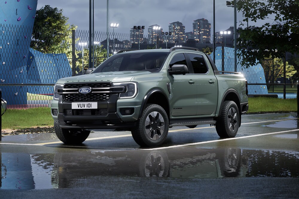 Grauer Ford Ranger PHEV parkiert in der Abenddämmerung vor einem urbanen Stadtbild.