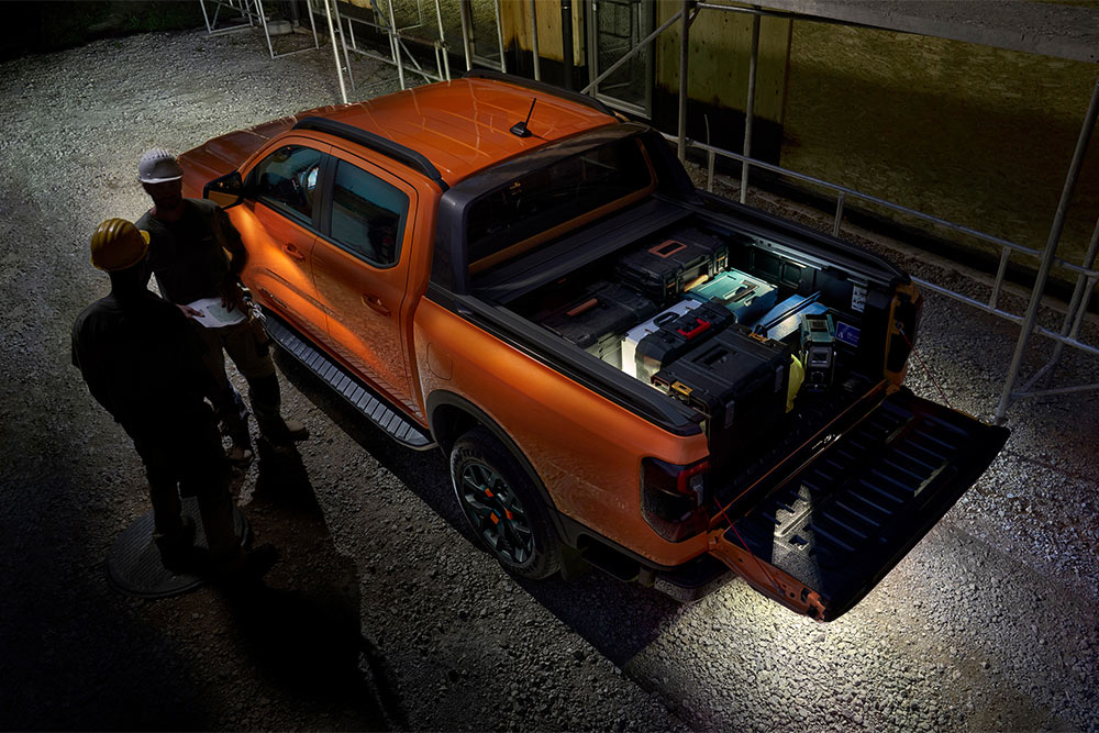 Blick von oben auf den orangefarbenen Ford Ranger Wildtrak bei Nacht mit Aussenbeleuchtung.