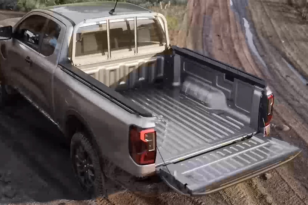 Blick von oben auf die geöffnete Ladebrücke eines silbernen Ford Ranger XLT mit Extrakabine, der auf  schlammigem Untergrund parkiert ist.