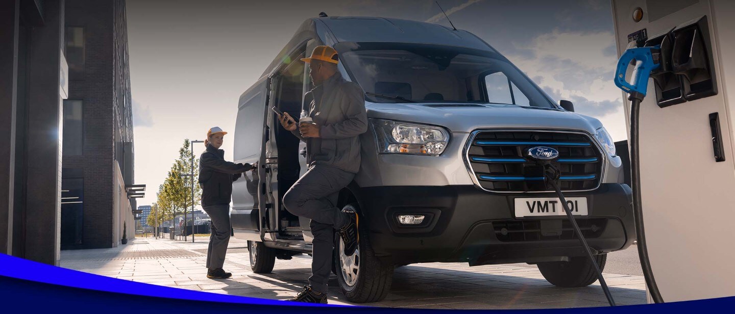 Zwei Arbeiter laden einen Ford E-Transit in Silber in der Frontansicht