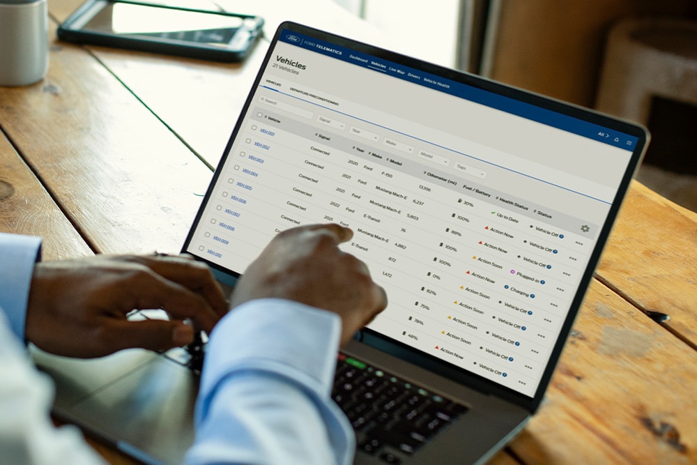 Ford Pro Flottenmanager betrachtet Fahrzeugdaten auf seinem Laptop.