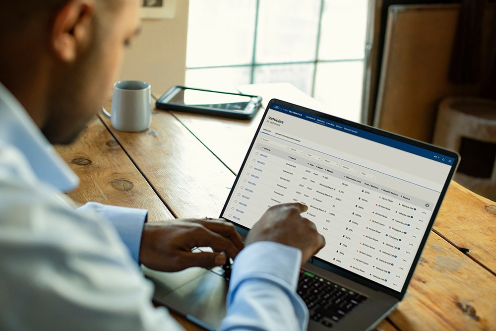 Ford Pro Flottenmanager betrachtet Fahrzeugdaten auf seinem Laptop.