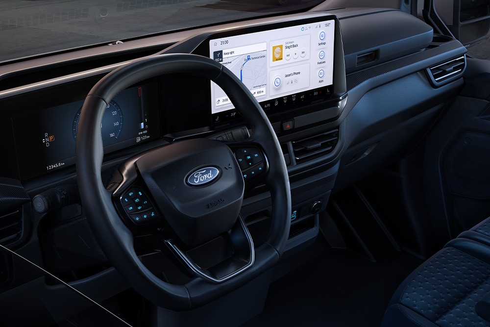 Innenansicht eines Ford-Fahrzeugs mit großem digitalem Armaturenbrett, das durch die Windschutzscheibe eine Baustelle zeigt.
