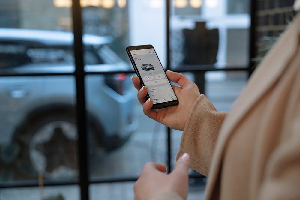 Eine Person hält ein Smartphone, auf dem die FordPass-App mit Flottenmanagement-Informationen angezeigt wird.
