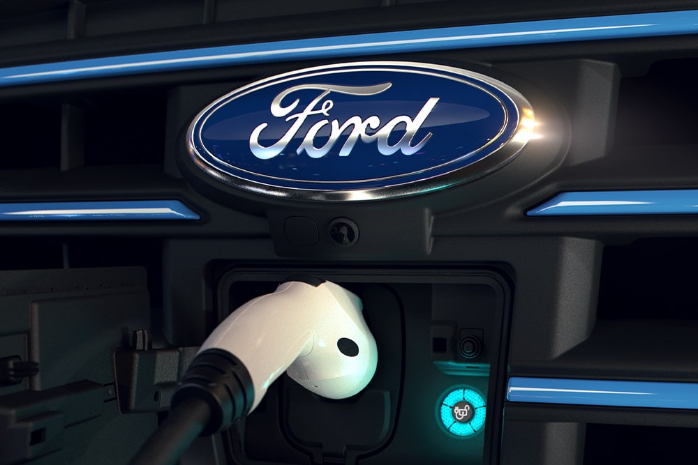Nahaufnahme eines weissen Ladekabels, das in den vorderen Ladeanschluss eines Ford-Elektrofahrzeugs eingesteckt ist.
