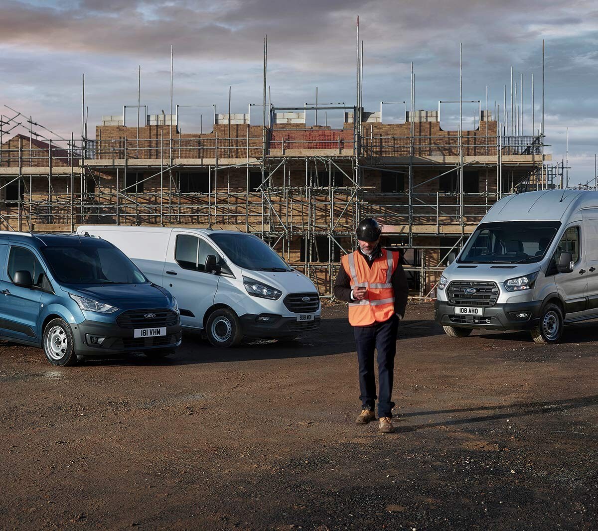 Arbeiter mit Bauhelm und Warnweste vor einer Baustelle mit Ford Fahrzeugen im Hintergrund