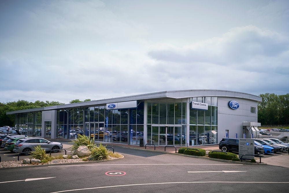 Aussenansicht eines Ford-Autohauses mit grossen Glasfenstern. Autos stehen draussen.