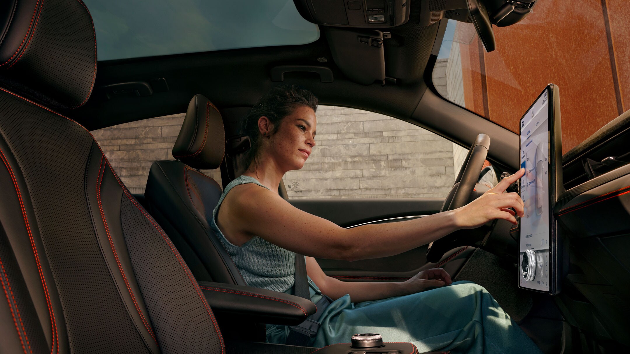 Innenansicht. Frau bedient vom Fahrersitz aus den SYNC 4A Touchscreen in ihrem Fahrzeug