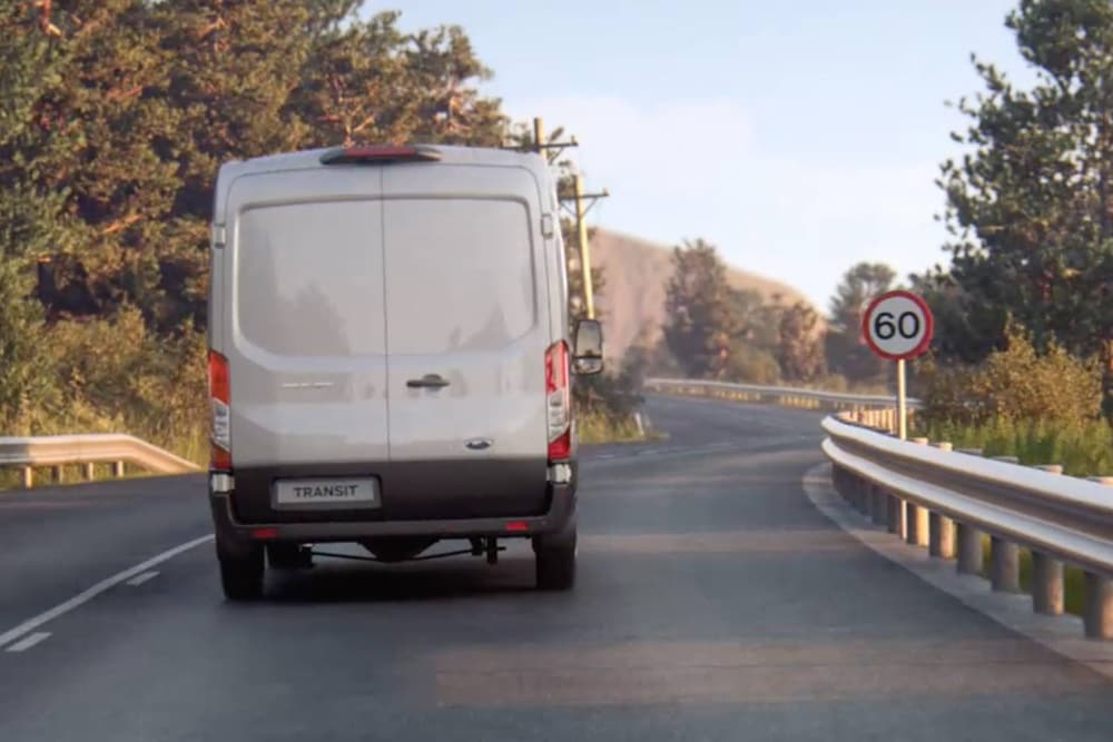 Ford Transit Van fährt auf der Strasse mit Verkehrsschild von hinten